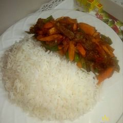 A picture of White rice and carrot sauce.