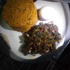 Jollof rice with steamed spinach A picture of Jollof rice with steamed spinach.