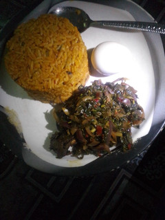 A picture of Jollof rice with steamed spinach.