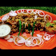 A picture of Hyderabadi biryani with mirch ka salan and garlic mint raita.