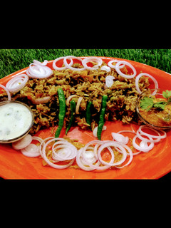 A picture of Hyderabadi biryani with mirch ka salan and garlic mint raita.