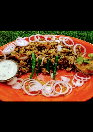 A picture of Hyderabadi biryani with mirch ka salan and garlic mint raita.