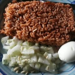 A picture of Jollof rice with cucumber and egg.