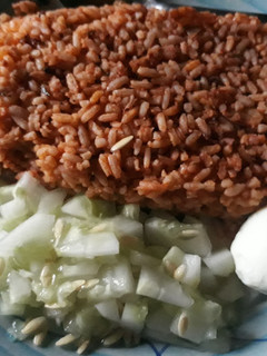 A picture of Jollof rice with cucumber and egg.