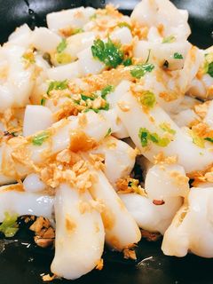Una foto de Sepia al ajillo con ajo crujiente y pimientos de Padrón