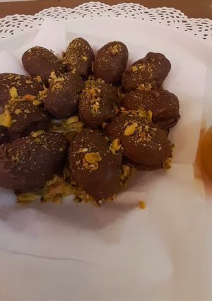 A picture of تمر محشي مكسّرات مغطى بالشوكولاتة.