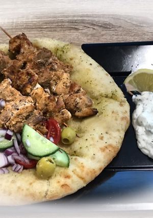 A picture of Greek Pork Souvlaki with Greek Salad and Flatbread.