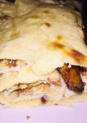 A picture of Fried egg and plantain wraped in pita bread.