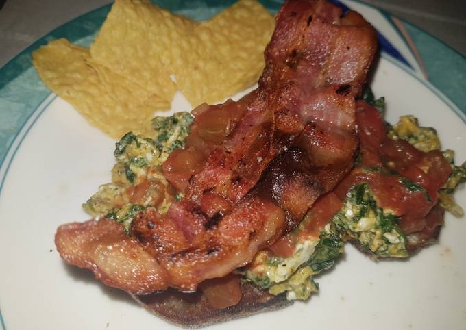 Spinach and egg scramble on rye bread, topped with crispy bacon