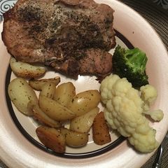 A picture of Pork chops with lemon roasted potatoes and veggies.