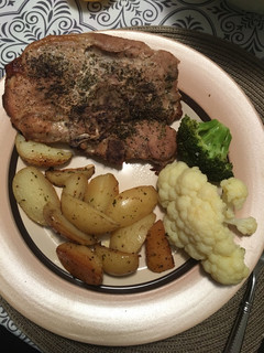 A picture of Pork chops with lemon roasted potatoes and veggies.