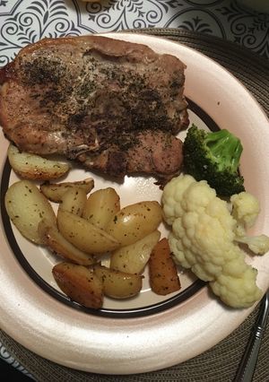 A picture of Pork chops with lemon roasted potatoes and veggies.