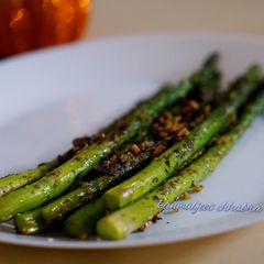 A picture of Burnt garlic aspagauraus topped with parmesan cheese.