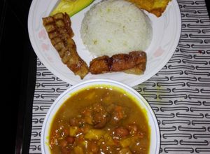 Una foto de Fríjoles con pezuña de cerdo, aguacate, patacón verde, arroz blanco y chicharrón