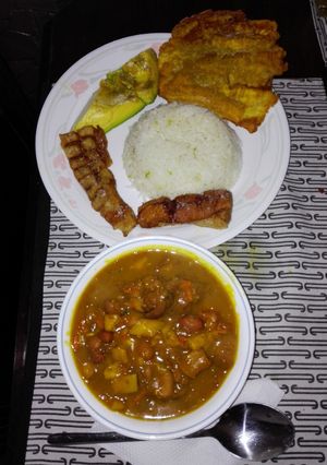 Una foto de Fríjoles con pezuña de cerdo, aguacate, patacón verde, arroz blanco y chicharrón