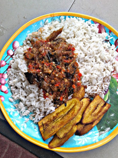 A picture of Rice and stew with fried plantain.