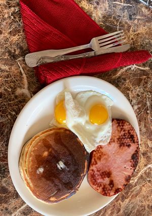 Una foto de Tortitas, jamón, y huevos con el sol arriba