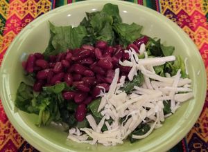 Una foto de Ensalada fresca de espinaca, porotos colorados y queso en hebras