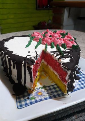 Una foto de Torta de colores con cobertura crema chantilly y chocolate
