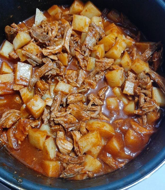 Una foto de Pierna de cerdo con papitas y chile rojo