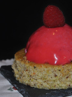 Una foto de Semiesferas de frutos rojos con glaseado espejo sobre bizcocho de pistacho