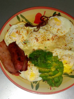 A picture of Fried eggs with fried beef and avacado.