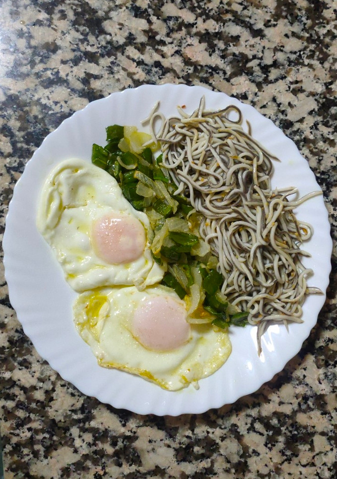 Una foto de Huevos fritos con gulas, pimiento verde y cebolla