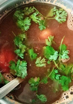 A picture of Basil leaves and tomato soup.