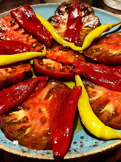 Una foto de Ensalada de tomate ibérico, pimiento asado dulce y piparras con sal de hierbas provenzales