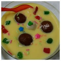 A picture of Gulab jamun floating in custard sauce.