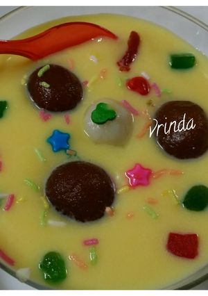 A picture of Gulab jamun floating in custard sauce.