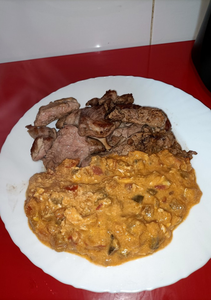 Una foto de Pisto revuelto con huevos y cabeza de lomo a la plancha