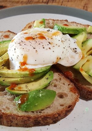 A picture of Soft poached egg and avocado on toasted sourdough.