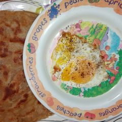 A picture of Wheat flour paratha with half fry egg.