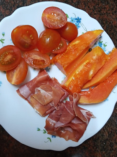 Una foto de Desayuno tropical: Papaya con jamón serrano y tomate cherry