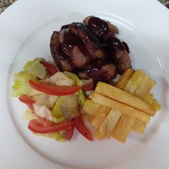 A picture of Medium-well done steak having red sauce, French fries and salad.