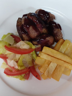 A picture of Medium-well done steak having red sauce, French fries and salad.