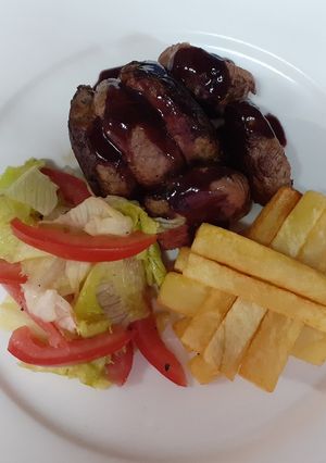 A picture of Medium-well done steak having red sauce, French fries and salad.