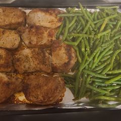 A picture of Pork chops with apples and green beans.
