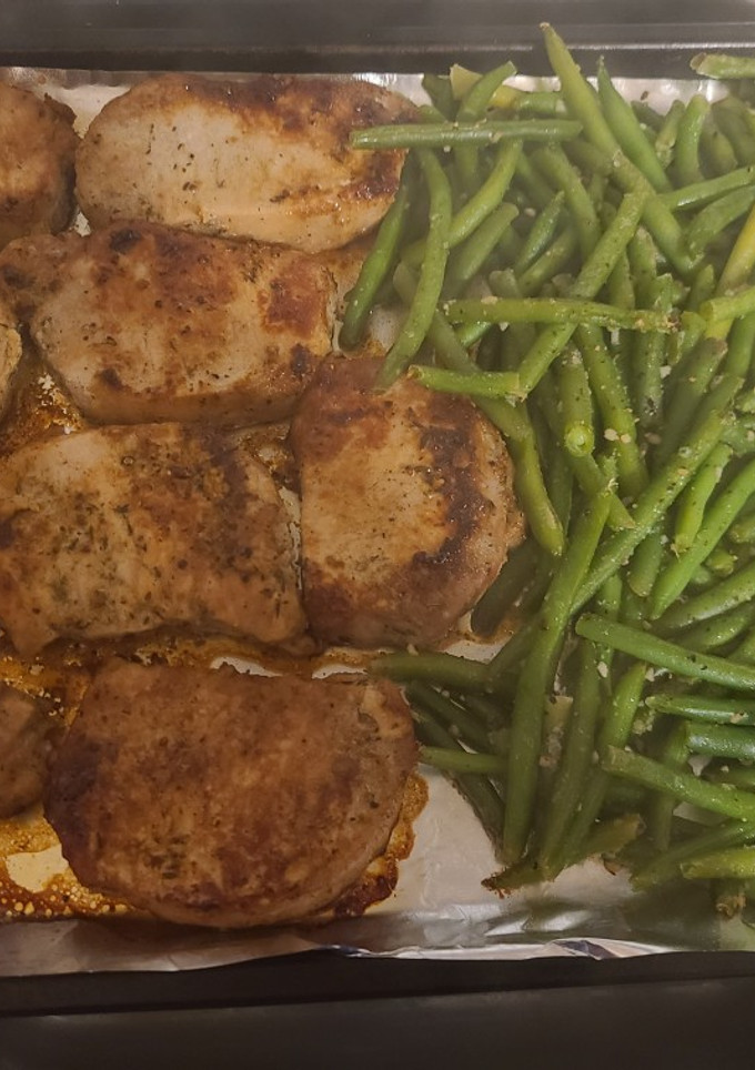 A picture of Pork chops with apples and green beans.