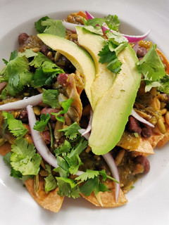 Una foto de Chilaquiles con elote asado, frijoles negros y pepitas