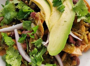 Una foto de Chilaquiles con elote asado, frijoles negros y pepitas