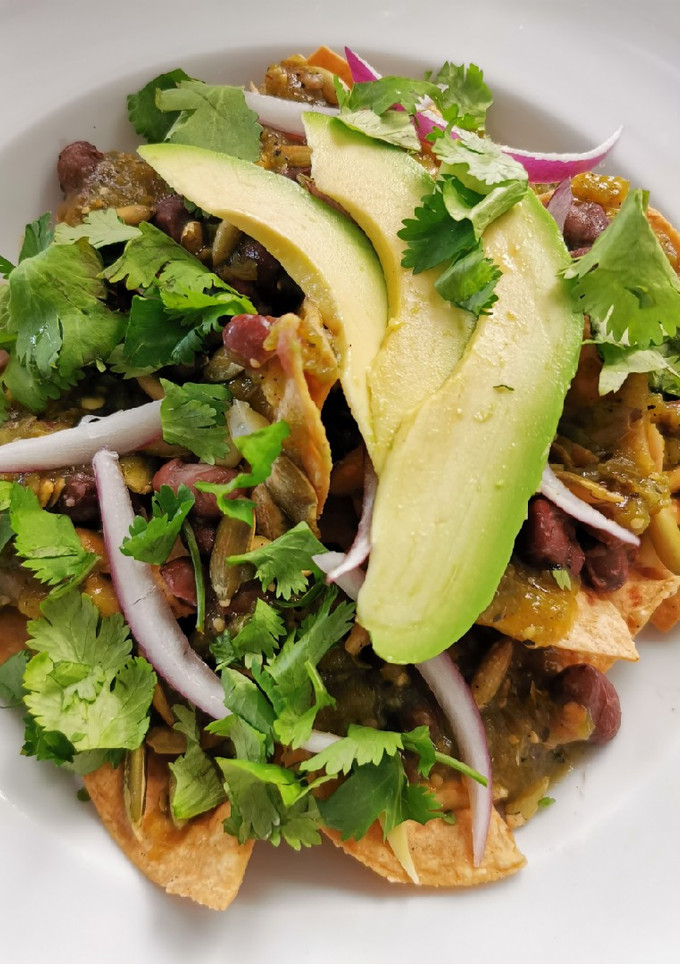 Una foto de Chilaquiles con elote asado, frijoles negros y pepitas
