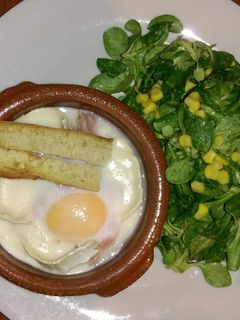 Una foto de Huevos en cocotte con queso de cabra y jamón y ensalada de canónigos con maíz