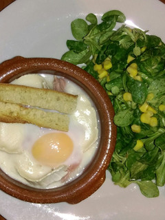 Una foto de Huevos en cocotte con queso de cabra y jamón y ensalada de canónigos con maíz