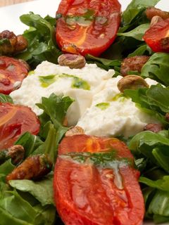 Una foto de Ensalada de rúcula con burrata, bacon y pesto de nueces