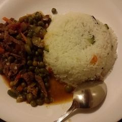 A picture of Rice served with beef and  peas stew.
