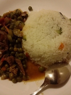A picture of Rice served with beef and peas stew.