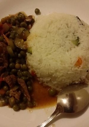 A picture of Rice served with beef and  peas stew.