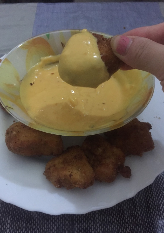 Una foto de Pollo frito con salsa cheddar 🍗 🧀